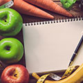 Comida variada, con una libreta y un boli en el centro de la imagen