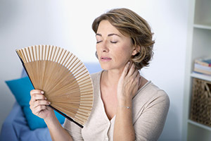 Mujer sufriendo sofocos por la menopausia