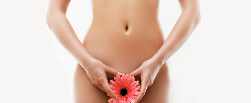 Cadera y cinturas de una mujer joven depilada, con un flor rosa ocultando la zona intima