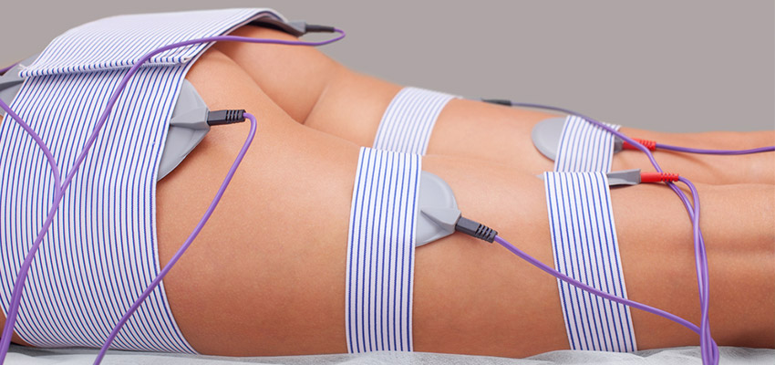 Piernas y trasero de mujer joven con aparato electroestimulador